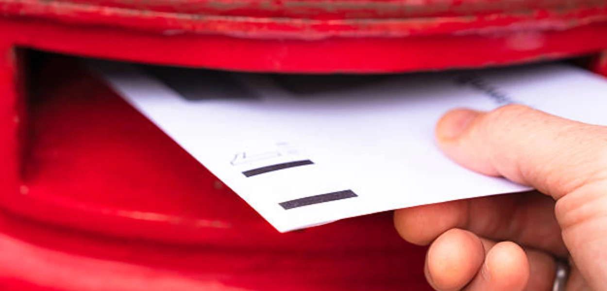 Gambar surat yang dimasukkan ke dalam kotak pos berwarna merah