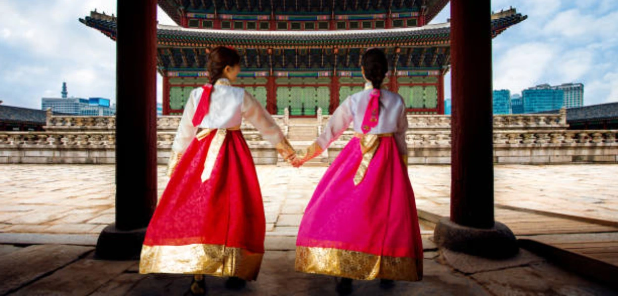 Gambar dua gadis mengenakan hanbok tradisional Korea di depan istana Korea